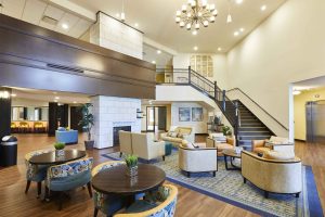 Lobby of senior living facility with wood paneling, white walls, and wrap up staircase