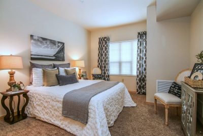 Apartment bedroom with cream colored walls, a large white bed