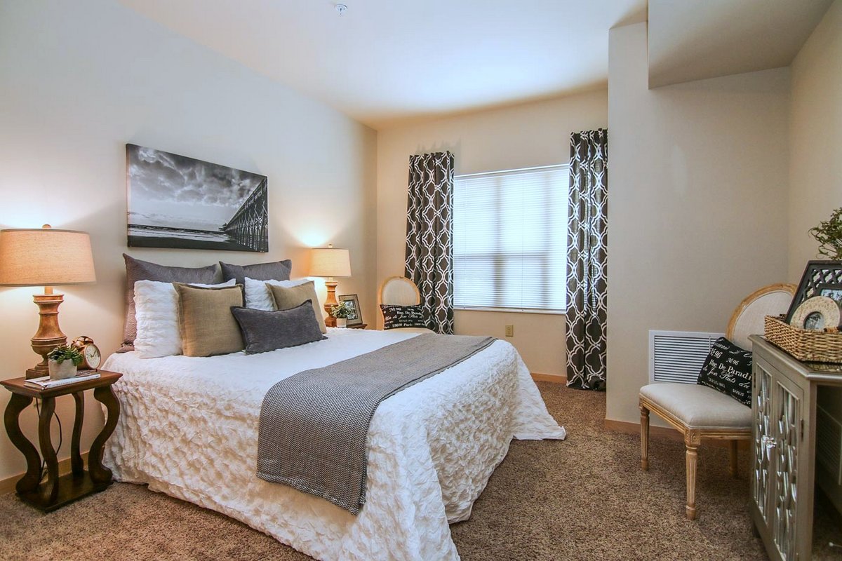 Apartment bedroom with cream colored walls, a large white bed