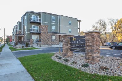 Exterior of Multi-story apartment building with brick signage, cream and sage green siding