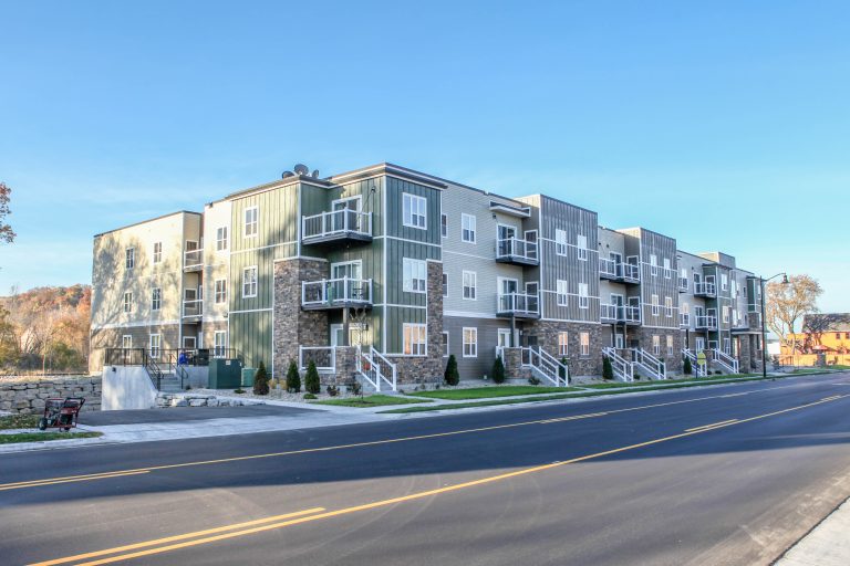 Exterior view from across the street of Multi-story apartment building with brick, cream and sage green siding