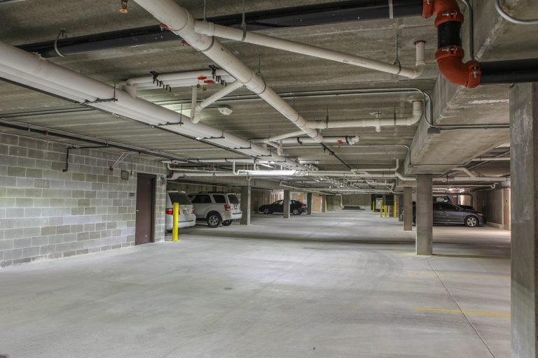 underground parking of Zander Place Apartments, concrete walls, floor and ceiling with white pipes running along the ceiling