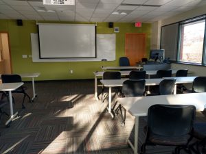 Classroom with lime green accent wall, seating and projector screen