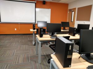 Bright orange accent wall with projector screen and computer desks