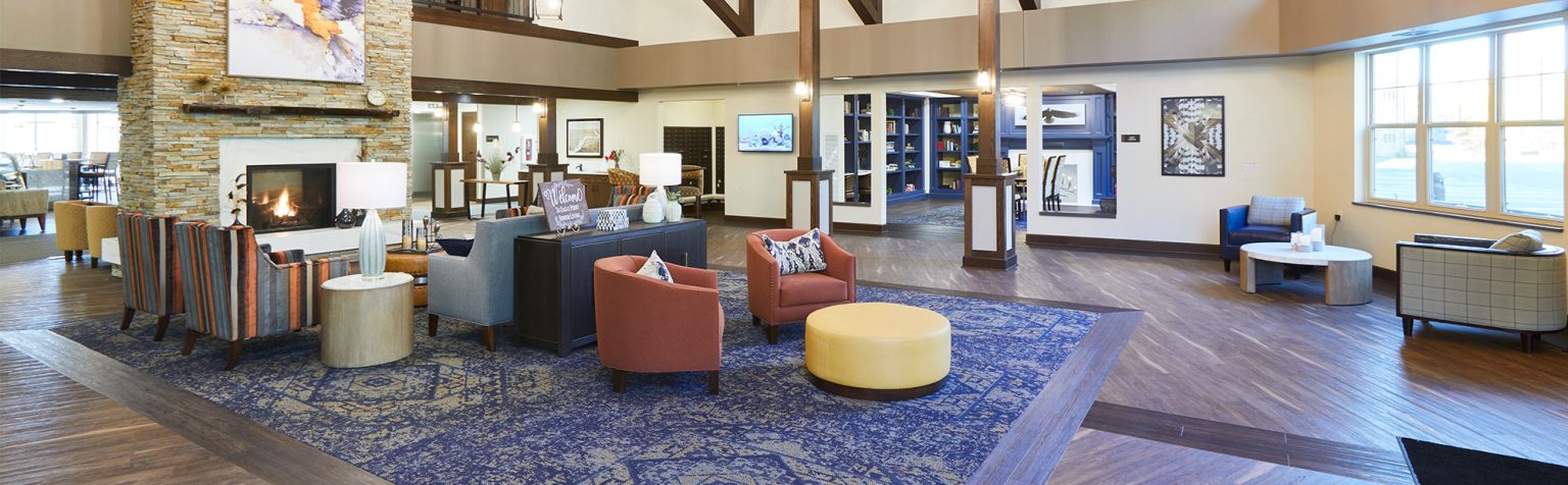 Senior Living facility lobby with vaulted ceilings, natural floor to ceiling fireplace, wood floors and lounge seating