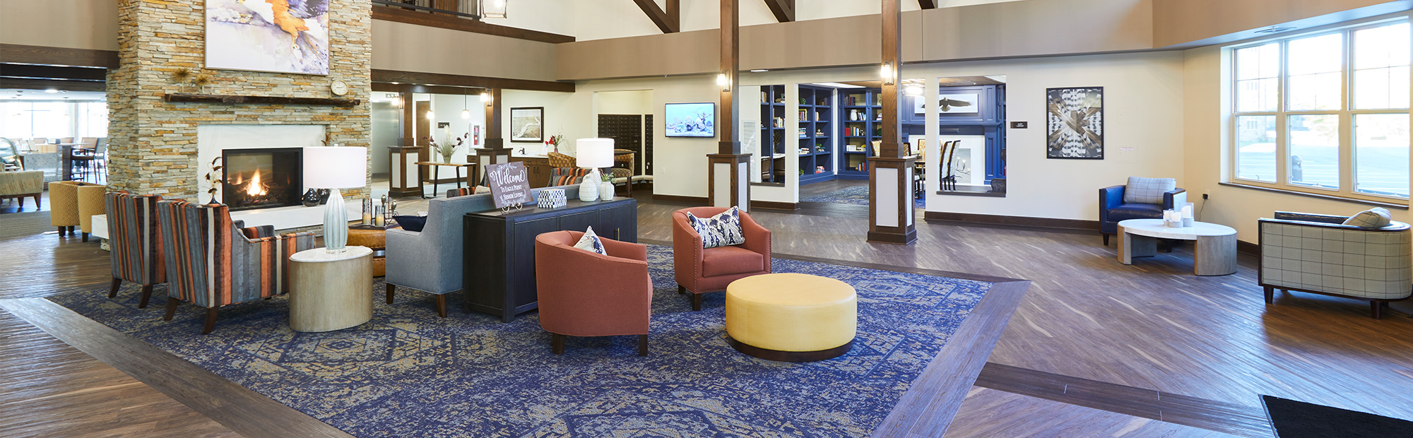 Senior Living facility lobby with vaulted ceilings, natural floor to ceiling fireplace, wood floors and lounge seating