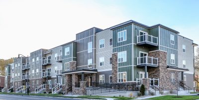 Exterior of Multi-story apartment building with brick, cream and sage green siding