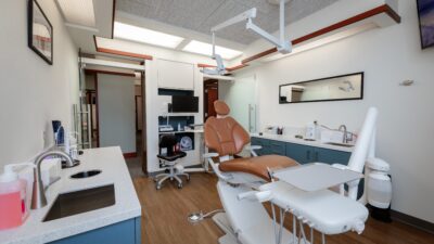 Dental lab with brown leather chair, glass doors and wood flooring