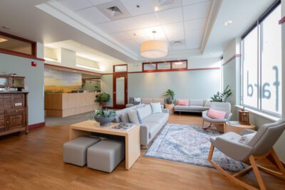 Fard Family Dental waiting area renovated by Iconica, featuring modern furniture, wood flooring, soft lighting, and a welcoming reception desk within a bright, comfortable dental office space.