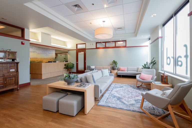 Fard Family Dental waiting area renovated by Iconica, featuring modern furniture, wood flooring, soft lighting, and a welcoming reception desk within a bright, comfortable dental office space.