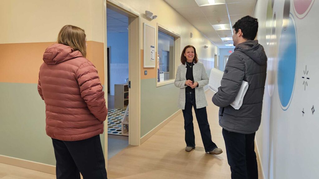 Iconica staff walking through a finished interior hallway during a building tour, discussing project details on site.