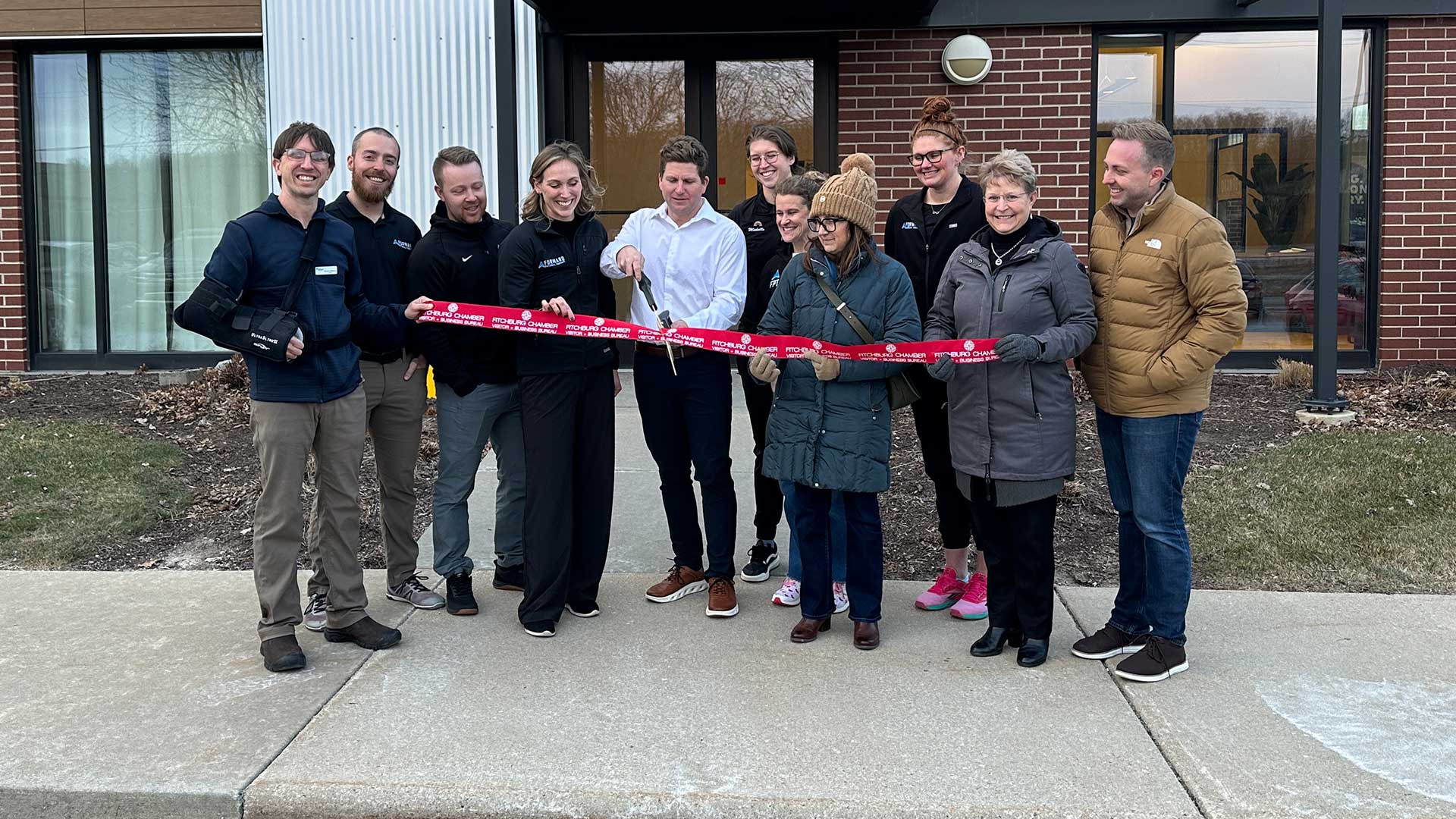 Forward Therapy grand opening ribbon cutting with staff and community members outside the clinic entrance in Fitchburg, Wisconsin