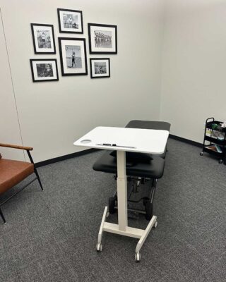 Private Physical Therapy Treatment Room With Adjustable Therapy Table, Rolling Tray, And Framed Wall Photos At Forward Therapy