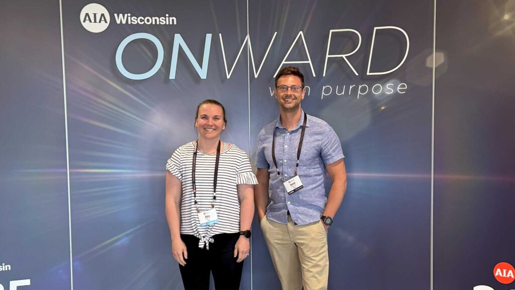 two iconica employees in front of sign at AIA conference 