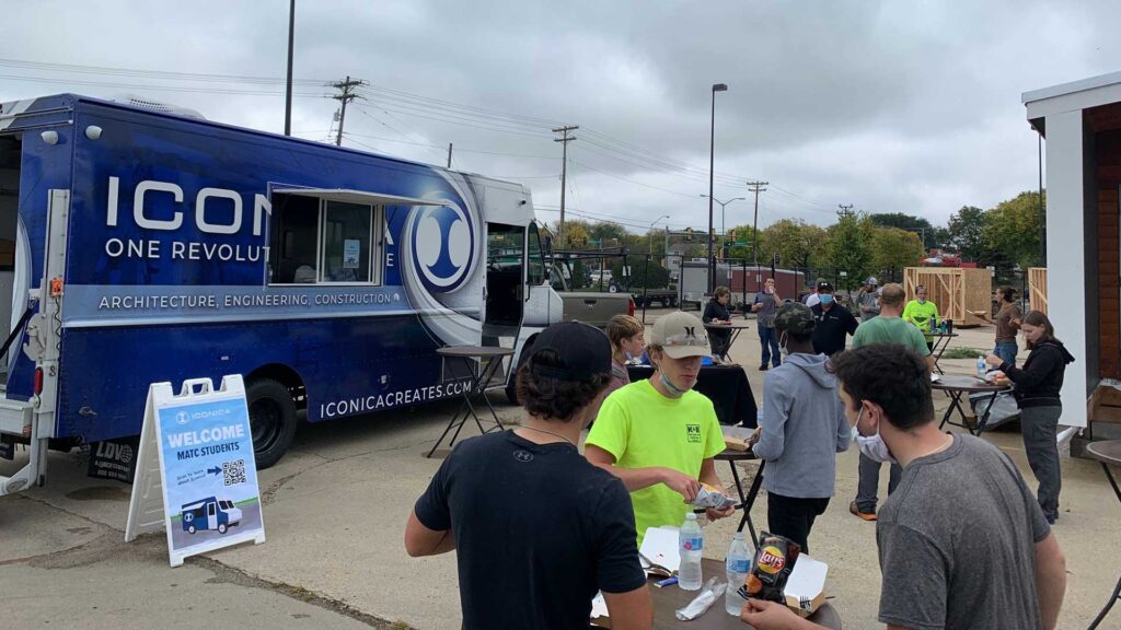 The Iconica "One Revolution" Food Truck Parked Outdoors On An Overcast Day With MATC Students Gathered At Nearby Tables Eating Lunch, Alongside A Welcome Sign Reading "Welcome MATC Students" With A QR Code.