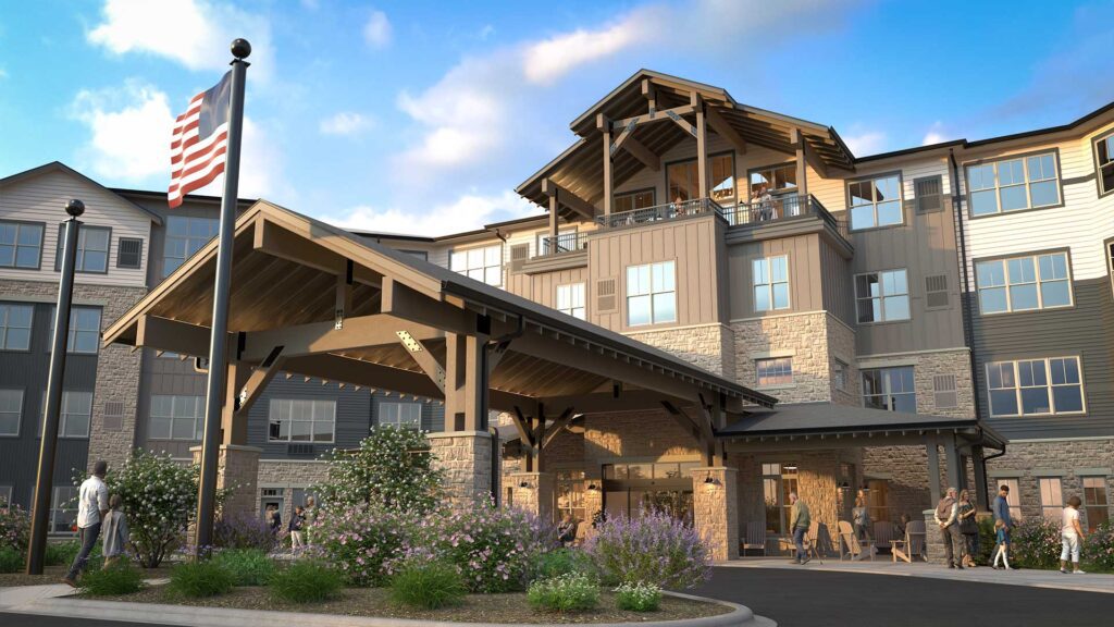 Front entrance rendering of LilyRose senior living, featuring a timber-frame porte-cochère, stone and wood siding, and landscaped entry with American flag.