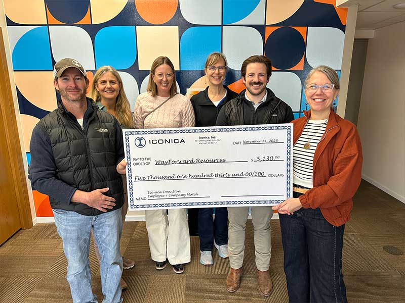 Group photo of team holding giant check that displays Iconica's donation