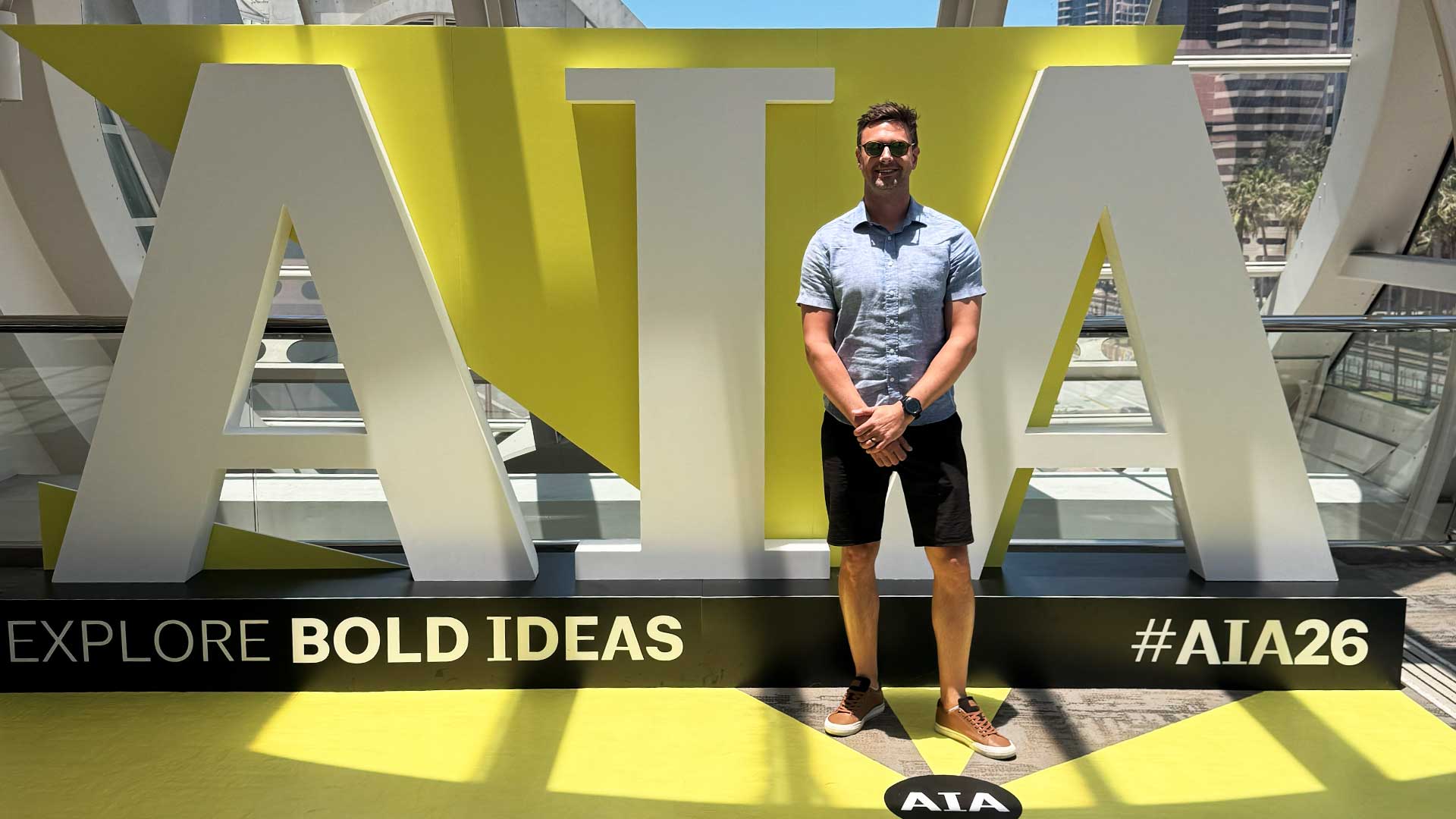 Iconica architect Devin poses in front of AIA26 conference signage at the AIA Conference on Architecture & Design 2026 in San Diego, California.