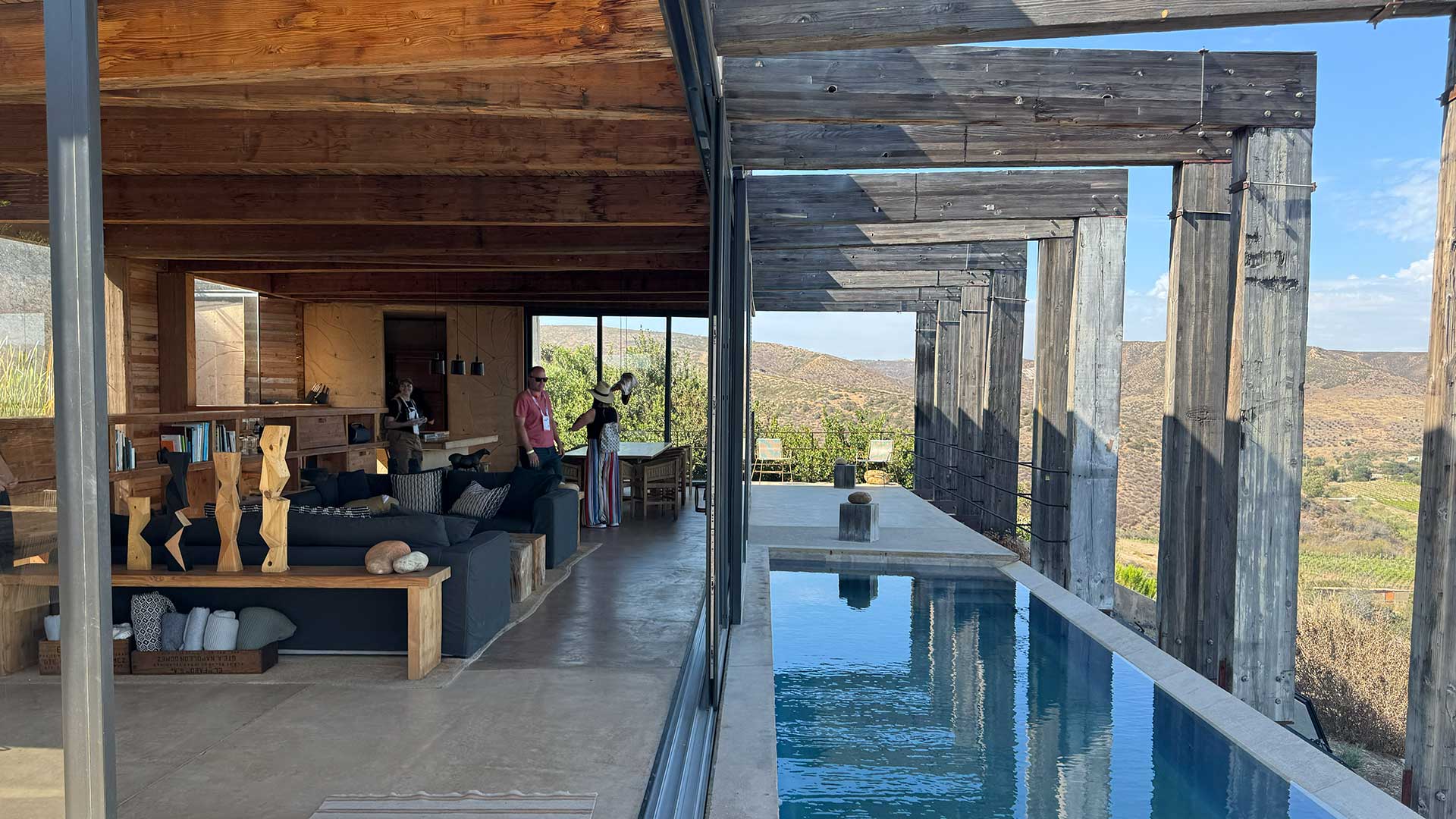 Modern residence at Quatro Cuatros in Valle de Guadalupe, Mexico, showcasing reclaimed wood materials, indoor-outdoor living, and vineyard views during an AIA architecture tour.