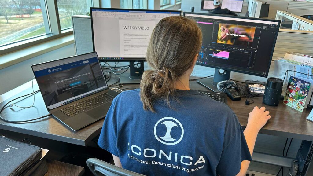 Female sitting at desk, editing video on desktop computer