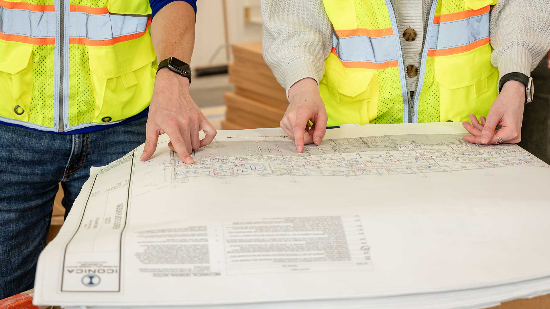 Iconica employees reviewing Iconica plans on a table top at a construction jobsite