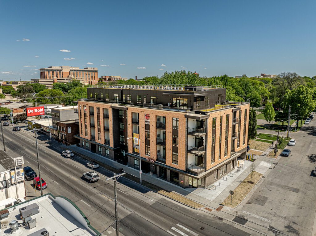 Aerial view of Vicino Apartments, a five-story brick apartment building on a Madison street corner