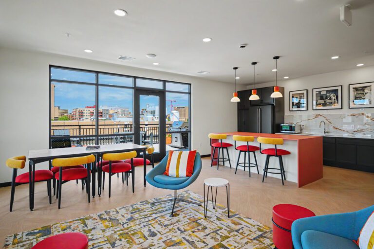 Vicino Apartments community room with shared kitchen, dining table, and lounge seating