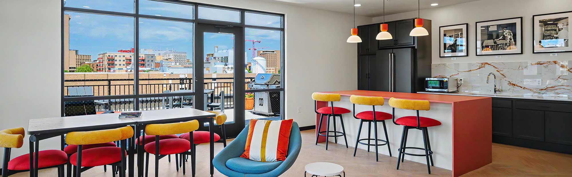 Vicinio Apartments community room with kitchen, dining seating, and rooftop terrace overlooking downtown Madison skyline