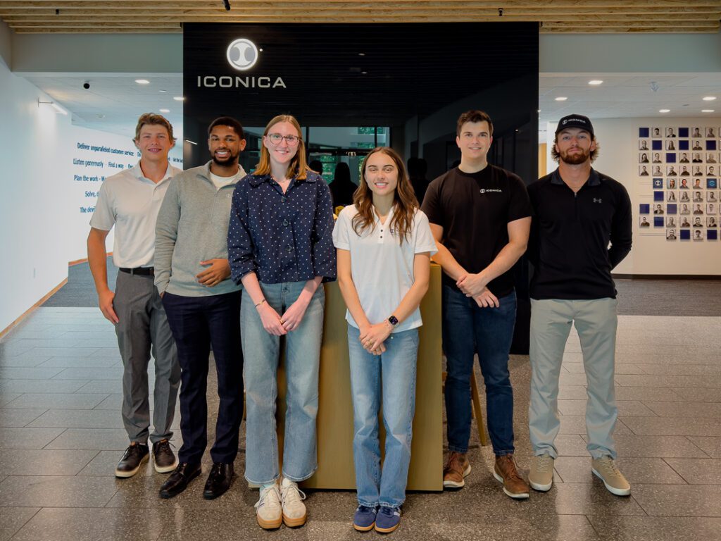 Group photos of similing interns standing in front of table in the Iconica lobbby