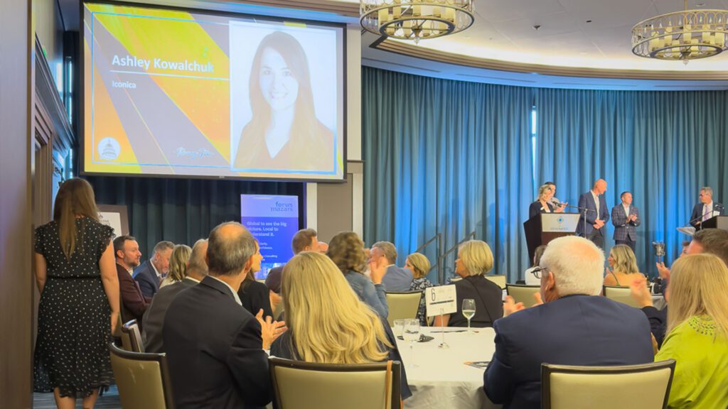 Screen displaying Ashley Kowalchuk's name and photo during the In Business Madison Executive Excellence Awards ceremony at the Edgewater