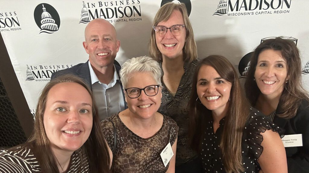 Iconica team members taking a group selfie in front of the In Business Madison step-and-repeat backdrop at the Executive Excellence Awards